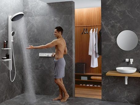 Ein Mann im Handtuch steht vor der Dusche im Badezimmer.